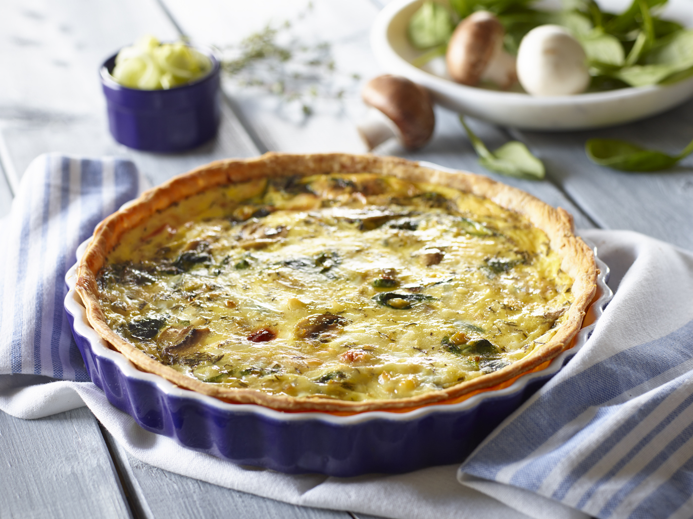 Freshly baked spinach quiche on wooden table